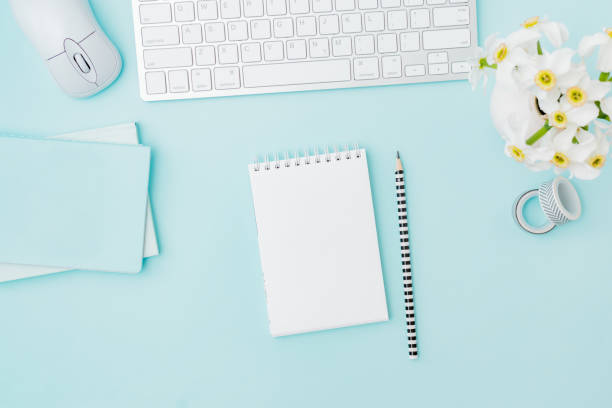 istock Flat lay blogger or freelancer workspace with a keyboard, notebook, flowers in a vase, office supplies on a color background 1225632189