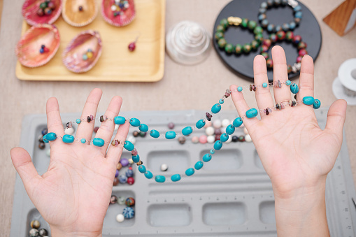 Handmade necklace made with turquoise and amethyst stones in hands of woman