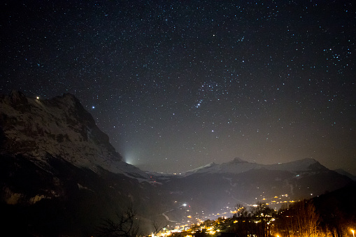 Light from town in valley competes with starlight above