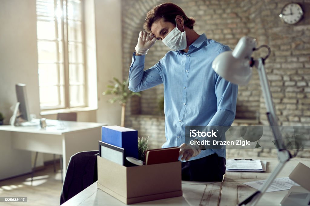 Male entrepreneur losing his job due to coronavirus epidemic. Young sad businessman packing his belongings after being fired during COVID-19 pandemic. Downsizing - Unemployment Stock Photo