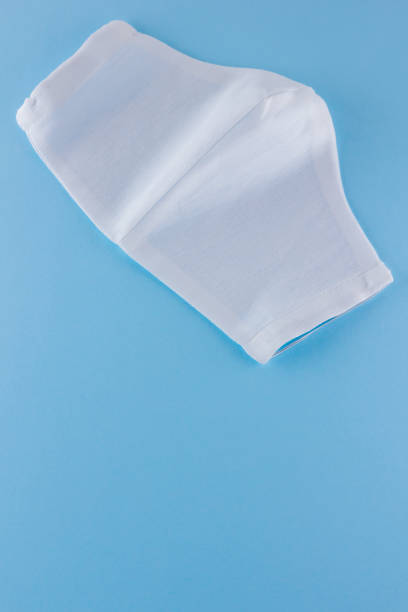 istock White antivirus mask. Protective gauze mask on a blue background. Handmade medical protective mask from cotton. Protective face mask made of gauze. Top view. Copy space 1225639705