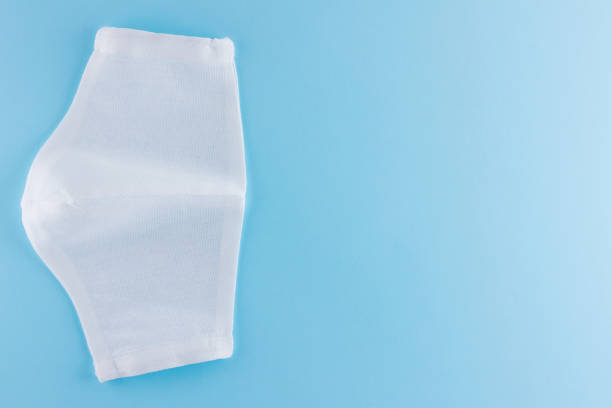 istock White antivirus mask. Protective gauze mask on a blue background. Handmade medical protective mask from cotton. Protective face mask made of gauze. Top view. Copy space 1225639725