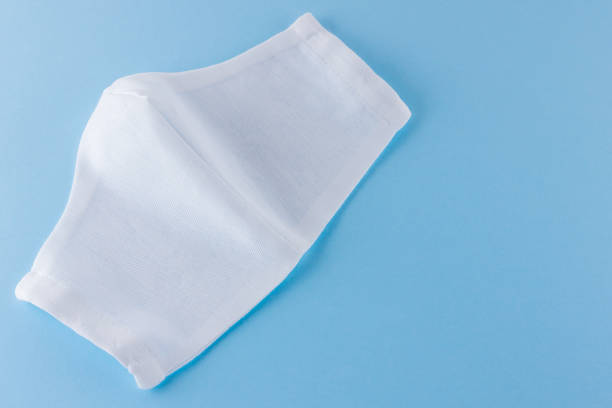 istock White antivirus mask. Protective gauze mask on a blue background. Handmade medical protective mask from cotton. Protective face mask made of gauze. Top view. Copy space 1225639747