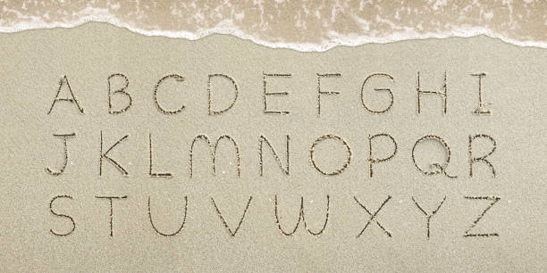 litery alfabetu odręcznie napisane w piasku na plaży - sand text alphabet beach zdjęcia i obrazy z banku zdjęć