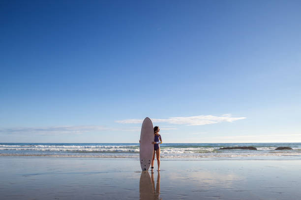 istock Girl holding surfboard at the beach 1225640212