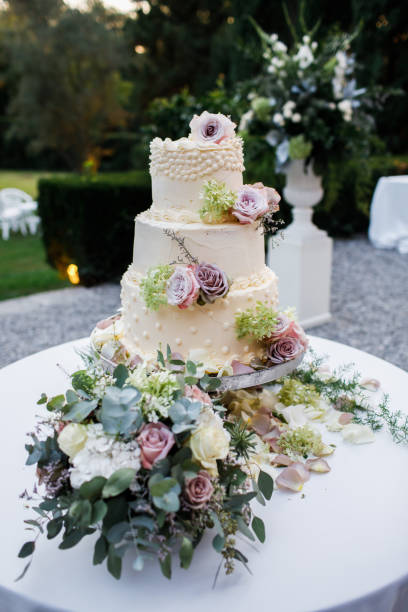 istock Wedding cake standing on the table. Around the flowers. 1225640459
