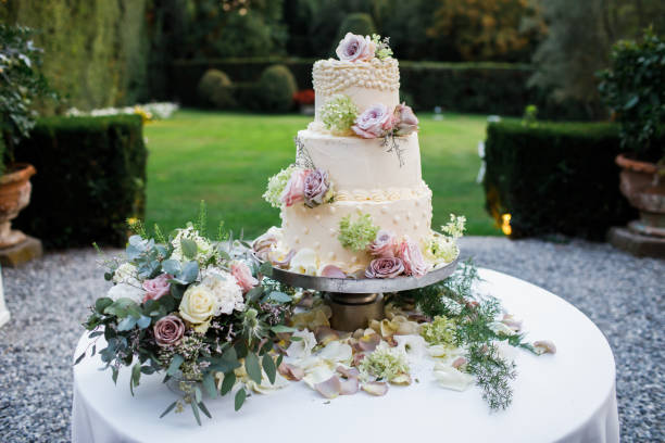 istock Wedding cake standing on the table. Around the flowers. 1225640477