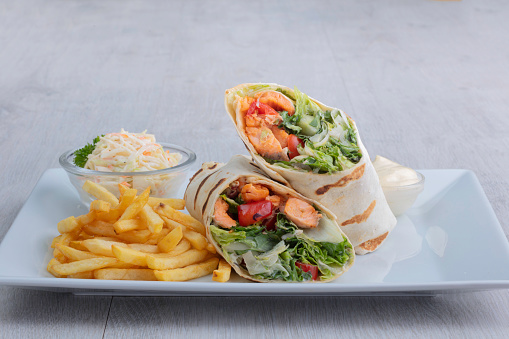wrap salmon with French fries and sauce on a white plate