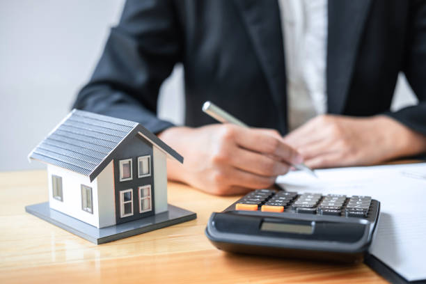 istock Real estate agent working sign agreement document contract for house insurance approving purchases for client with house model and key on table 1225649450