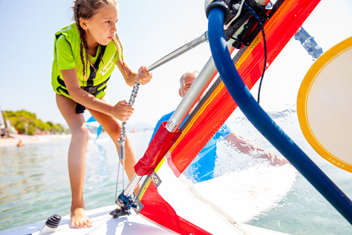 Little Girl Using the Uphaul to Rise the Windsurf Sail - Stock Photo