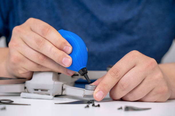 istock Man maintains drone using silicone dust blower cleaner tool for digital camera lens and other plastic or glass surfaces at a table. 1225652581