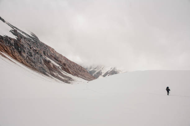 istock Man climbing on the snow on the mountain with hiking sticks and backpack 1225654279