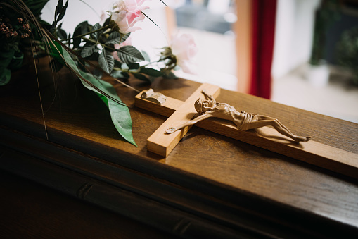 photo of a cross on a wooden casket at a funeral