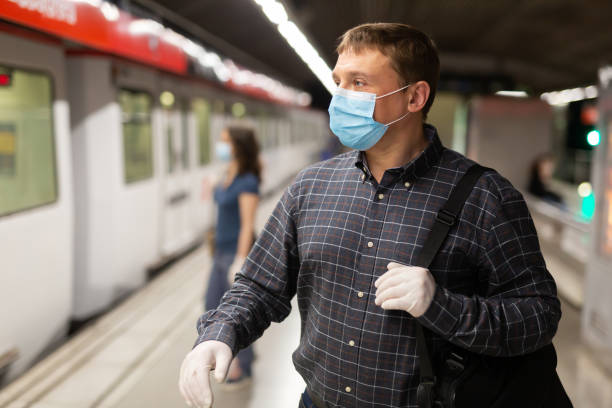 istock Man in protective medical mask is looking on railway and waiting train on platform in the underground 1225655925