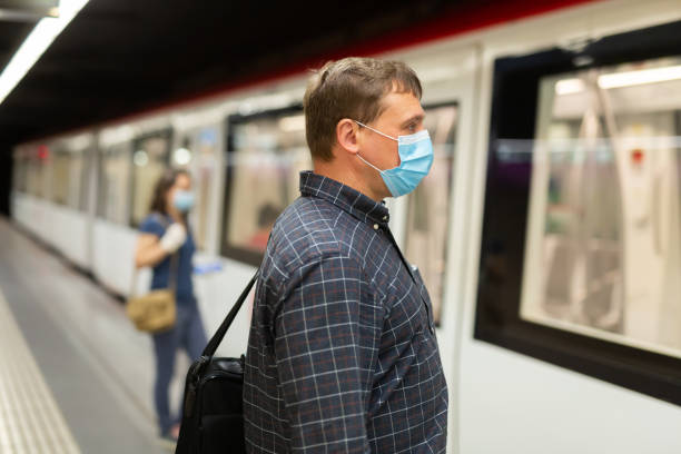 istock Man in protective medical mask is looking on railway and waiting train on platform in the underground 1225656810