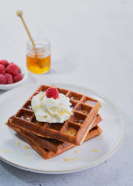 istock Homemade waffles with honey, raspberry, peaches in syrup in plate on grey surface. Healthy breakfast, brunch concept, selective focus, copy space. 1225657408