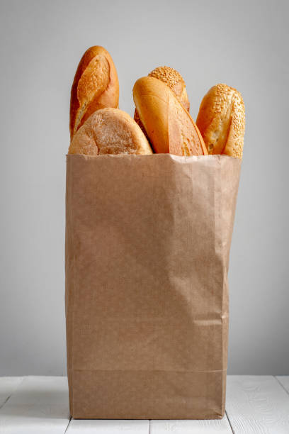 a paper bag with bread on the grey background. - papel de pão imagens e fotografias de stock