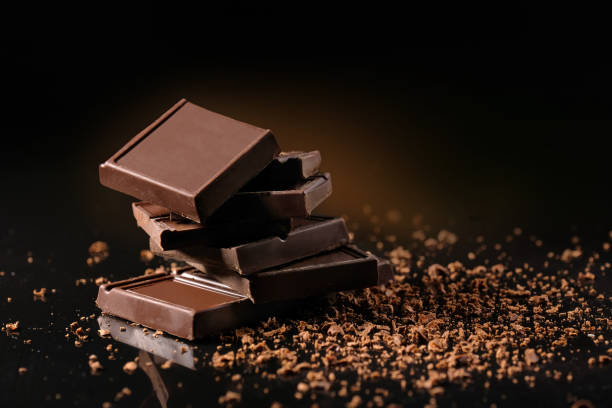 istock Broken chocolate and chocolate powder on a black background in the studio. 1225659314