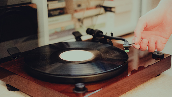 Closeup of young woman playing vinyl records at home in cozy setting, copy space