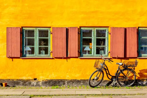 Photo of Old yellow house of Nyboder district with a bicycle. Old Medieval district in Copenhagen, Denmark