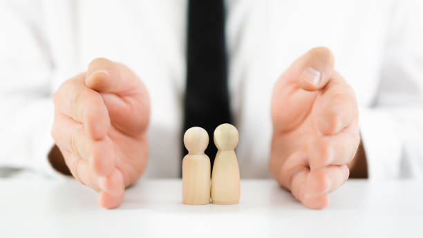 istock Wooden figures representing children with male hands making protective gesture around it in a conceptual image 1225663624