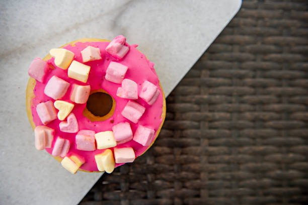 istock One pink donut with small marshmallows on a marble tray stands on a wicker brown tray 1225665241