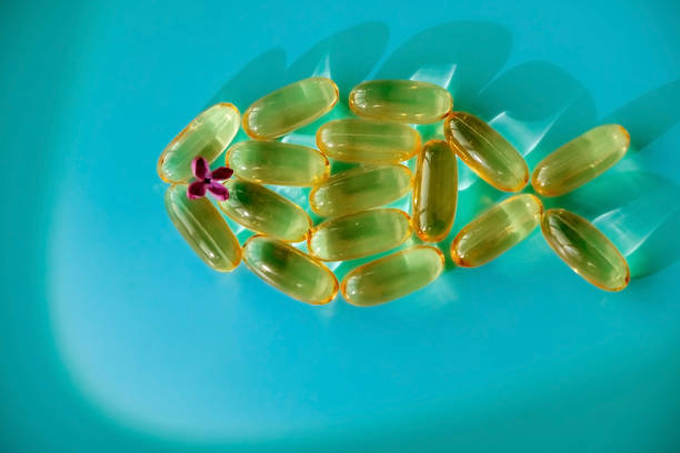 오메가 3 푸른 배경에 물고기의 형태로 캡슐 - vibrant color healthcare and medicine healthy lifestyle vitamin pill 뉴스 사진 이미지