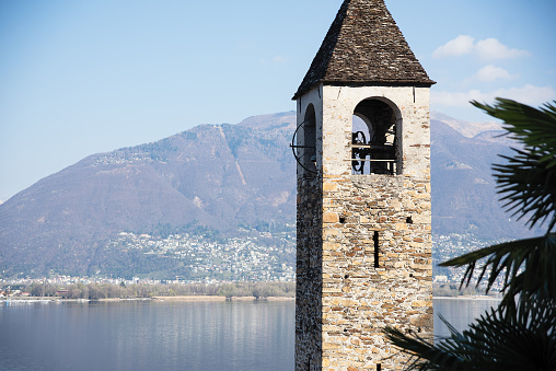 brick tower with a bell tower on the background of a lake, sky and mountains
