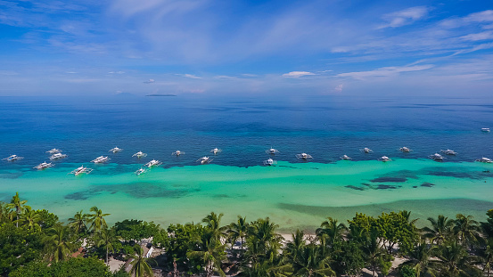 Aerial view of white sand beach, turquoise blue sea water and coconut palm trees in a tropical resort in Panglao Island, Bohol, Philippines.