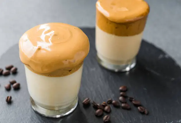 Photo of Dalgona coffee whipped cream mousse against grey background, also dubbed as quarantine drink