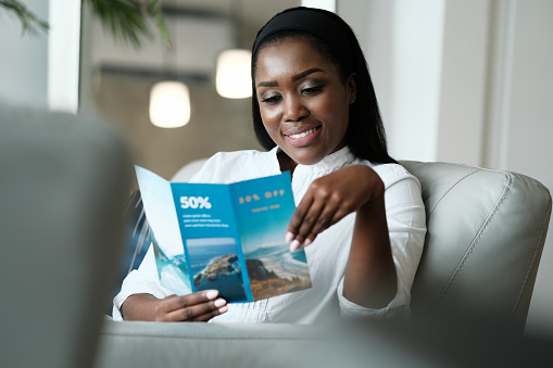 Mujer negra leyendo volante de viaje para un viaje de vacaciones photo