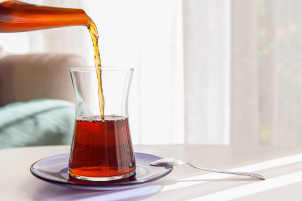 Blacktea, tea is pouring from teapot and tea glass served on coffee table stock photo