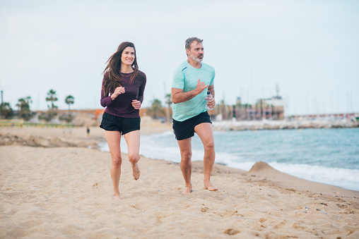 Couple jogging on the beach in the morning.