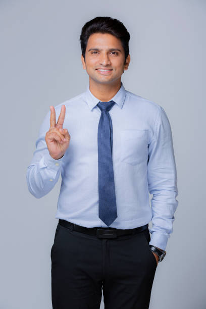 Young Indian businessman - stock photo Men, White Background, Businessman, Button Down Shirt, Shirt man showing peace sign stock pictures, royalty-free photos & images