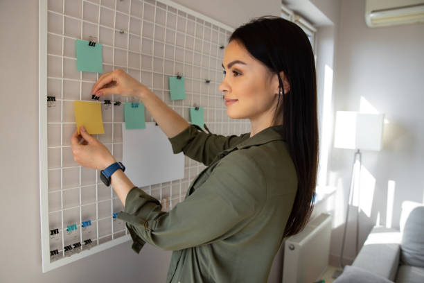 istock Smiling lady putting notes on the mesh board stock photo 1225706431