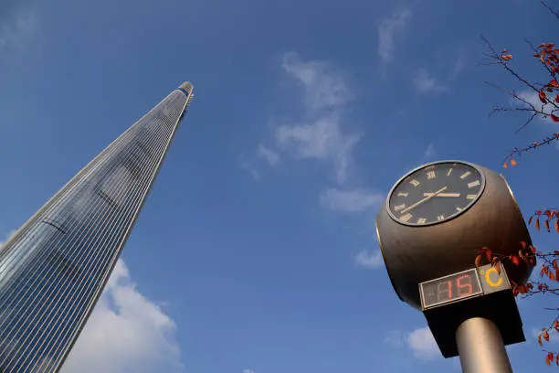 Low angle view of a clock  and the Lotte World tower, the highest skyscraper in Seoul, height 555 mt. in Seoul, South Korea.