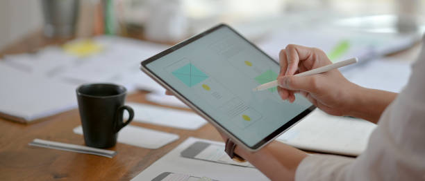 istock Side view of professional UI developer concentrating on his project with digital tablet and paperwork 1225716551