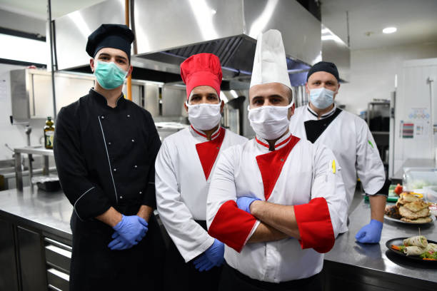 istock group chefs standing together in the kitchen at restaurant wearing protective medical mask and gloves in coronavirus new normal concept 1225719325