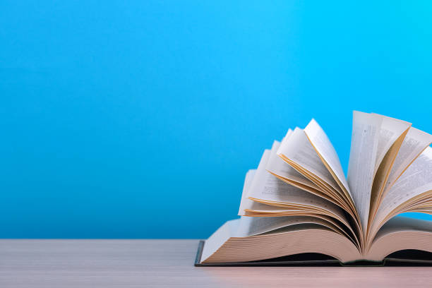 istock The book is open, lying on the table, sheets fanned out on a blue background. 1225719675