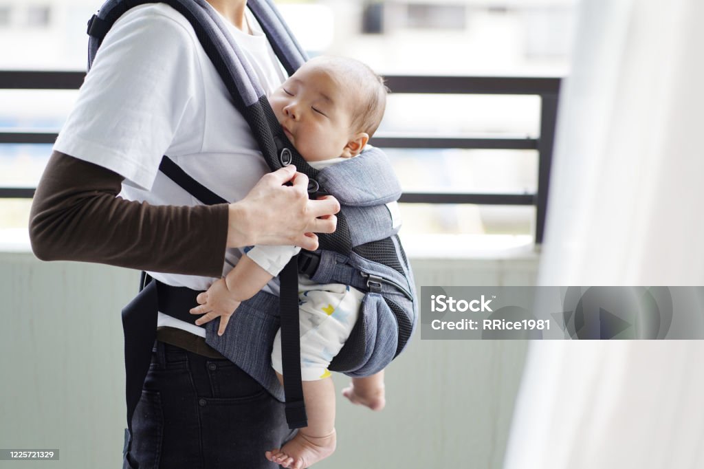 A mother and her five-month-old baby on a walk by baby carrier Baby Carrier Stock Photo