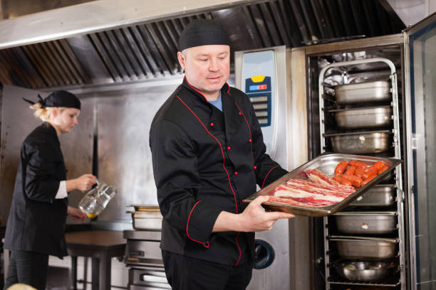 istock Cook putting pork ribs and sausages into oven 1225722274
