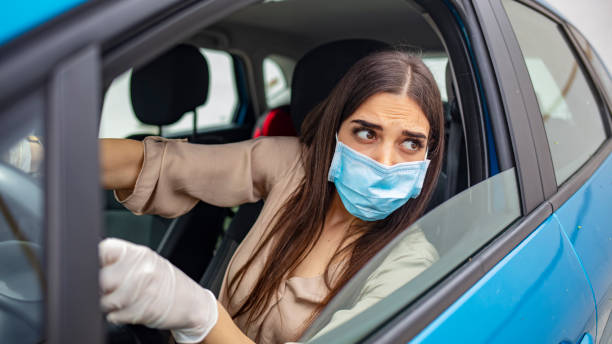istock Woman driving car while wearing protective mask. 1225723921