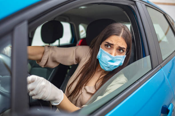 istock Woman driving car while wearing protective mask. 1225724452