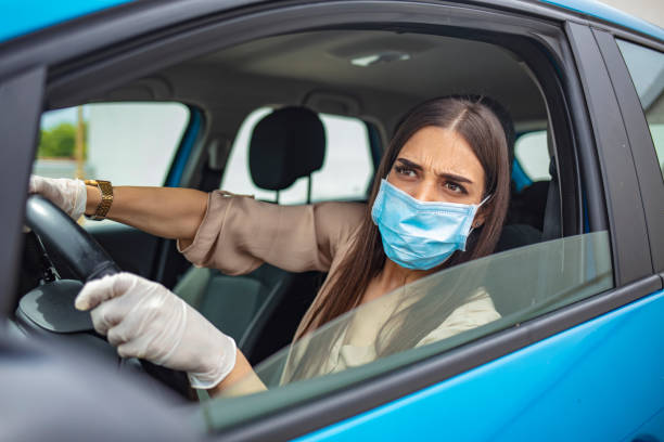 istock Woman driving car while wearing protective mask. 1225724454
