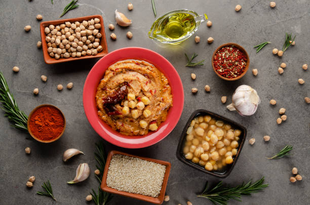 istock Hummus topped with chickpeas, olive oil and sun dried tomato on stone table with different spices aside. Flat lay 1225729909