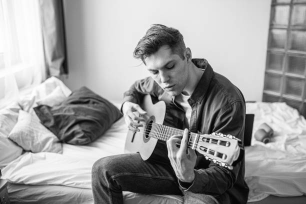 istock handsome man try to play guitar at home 1225734908
