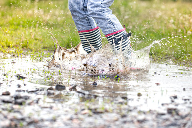 istock A child in rubber boots jumps in a puddle. 1225737539