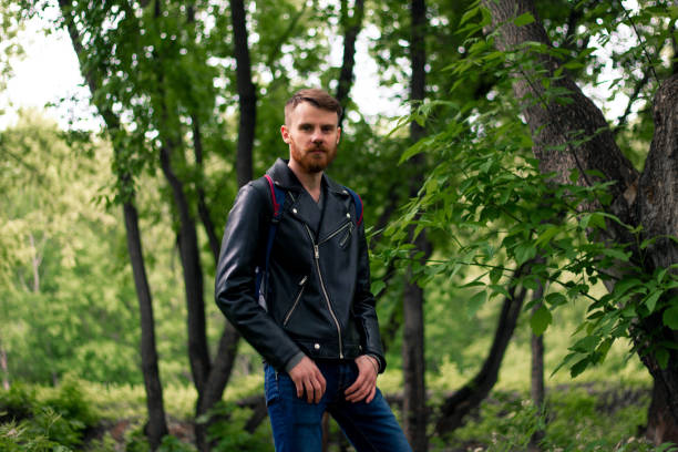 istock A guy with a red mustache in a leather jacket and blue jeans stands in the forest with his hands in the feed 1225737592