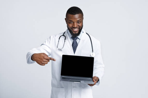 istock Black cheerful doc pointing at blank laptop screen 1225743387