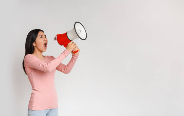 istock Agressive asian girl screaming towards copy space, using megaphone 1225744439